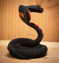Indlæs billede i Gallery viewer, MM Figur Sacky Serpent (13 cm) er en sort, sammenrullet voodoo-slangefigur med røde syninger, der står oprejst på en træplade - perfekt som hyldeudsmykning.
